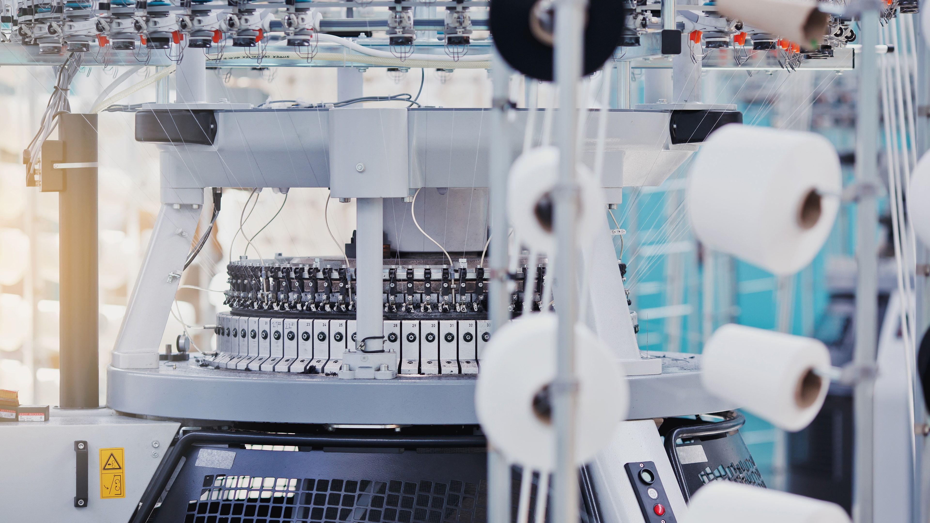 Máquina circular industrial tejiendo tubo de punto en una fábrica textil